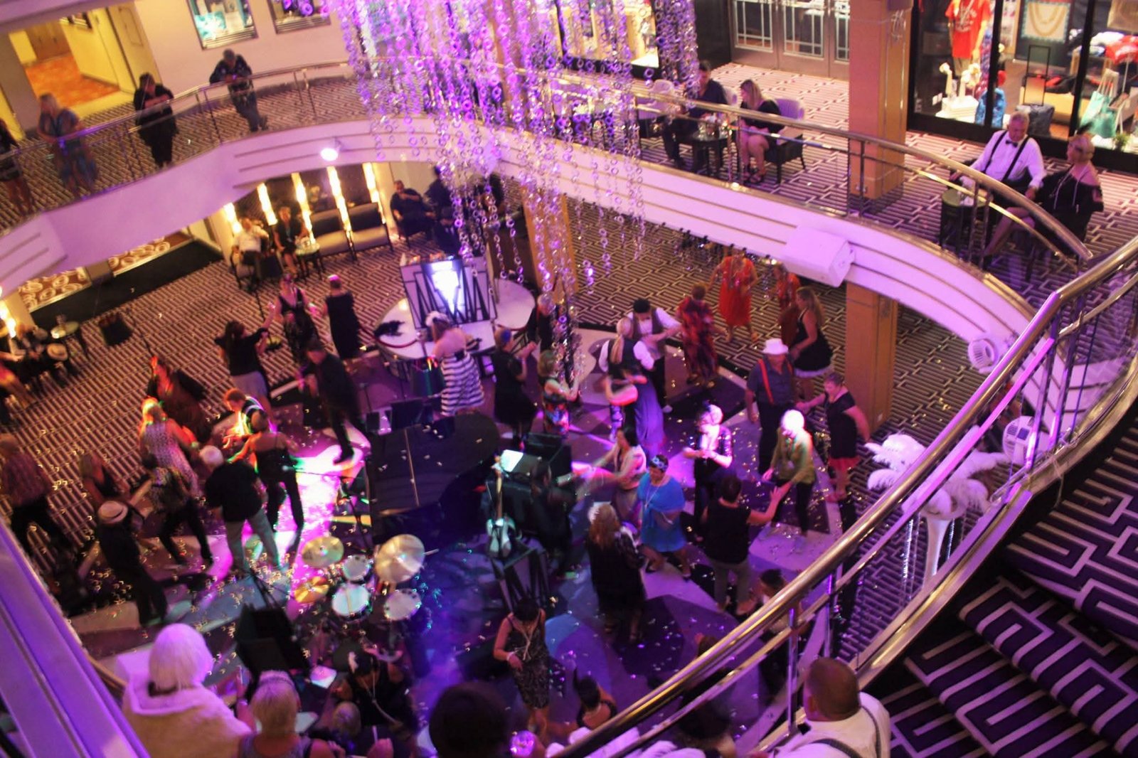 Passengers dressed up for a themed evening on the dance floor in the atrium of a cruise ship