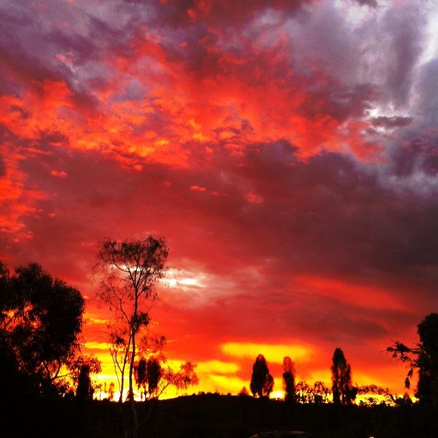 Uluru glowing red under a desert sky